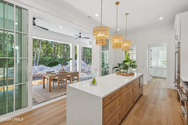 kitchen featuring white cabinetry, a center island, hanging light fixtures, light wood-type flooring, and stainless steel microwave