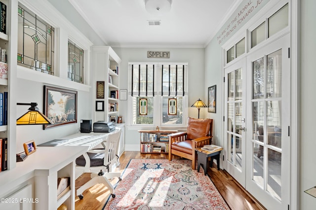 sitting room with visible vents, crown molding, and wood finished floors