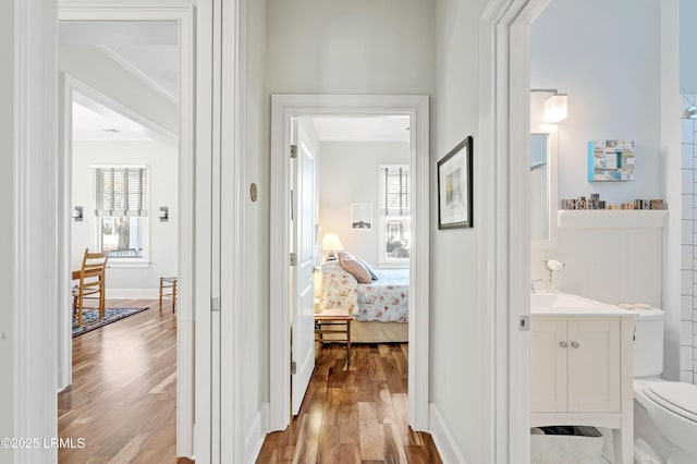 hallway featuring light wood-style flooring and crown molding