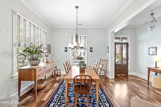 dining room with ornamental molding, wood finished floors, baseboards, and an inviting chandelier