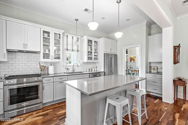 kitchen with stainless steel appliances, a sink, decorative light fixtures, and white cabinets