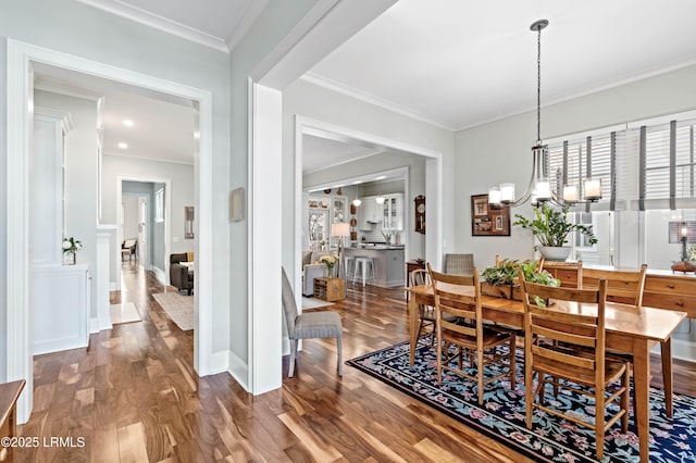 dining room with baseboards, ornamental molding, wood finished floors, and an inviting chandelier