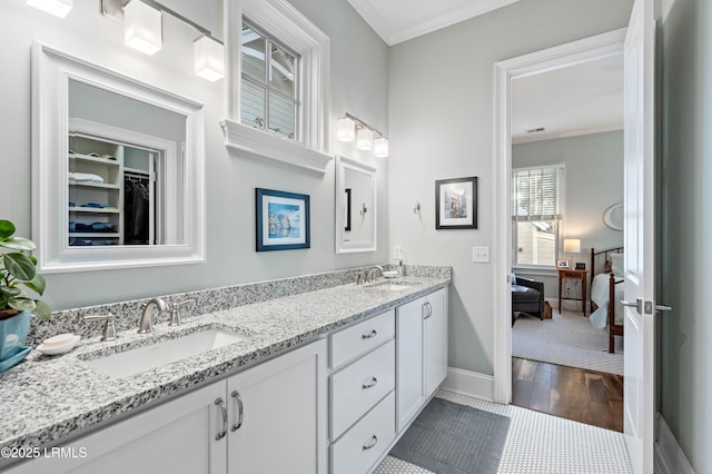 full bath featuring double vanity, ornamental molding, a sink, and baseboards