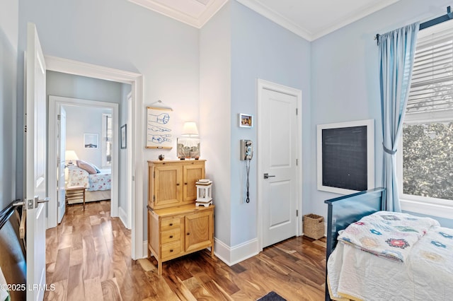 bedroom with ornamental molding, baseboards, and wood finished floors