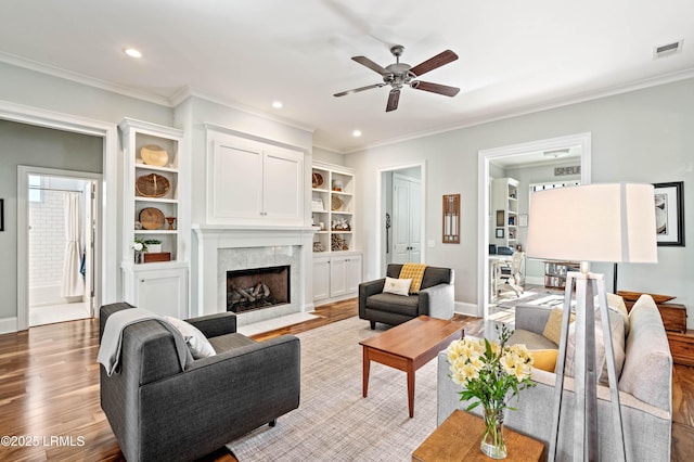 living room with ornamental molding, a premium fireplace, and light wood-type flooring