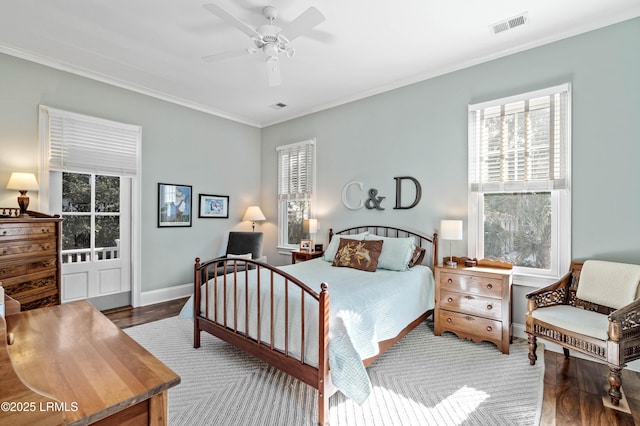 bedroom with ornamental molding, wood finished floors, visible vents, and baseboards