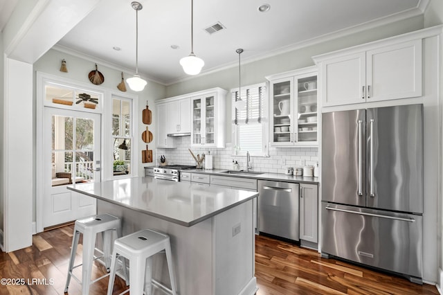 kitchen featuring a sink, white cabinetry, premium appliances, and decorative light fixtures