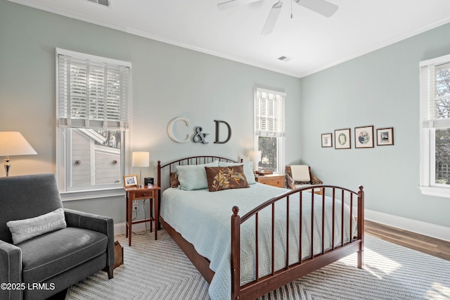 bedroom featuring ceiling fan, wood finished floors, visible vents, baseboards, and ornamental molding