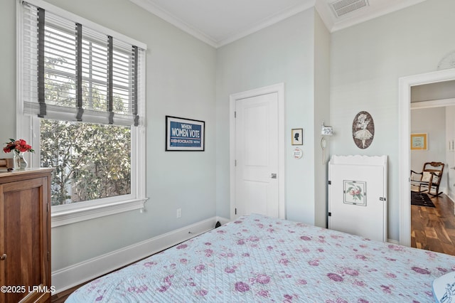 bedroom featuring ornamental molding, visible vents, baseboards, and wood finished floors