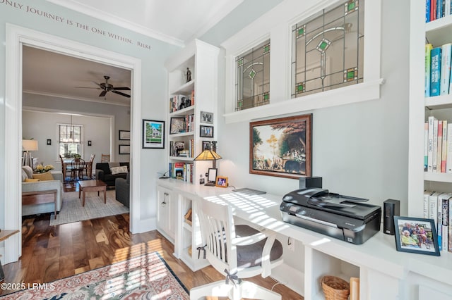 home office with ceiling fan, built in desk, dark wood-style flooring, and crown molding