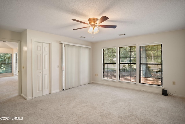 unfurnished bedroom featuring light carpet, two closets, and ceiling fan