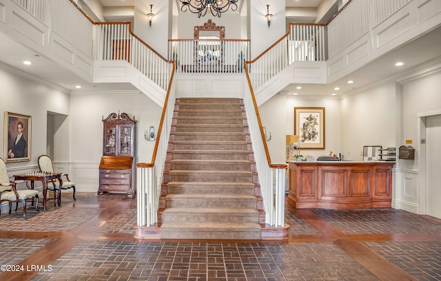 stairway with crown molding and a towering ceiling