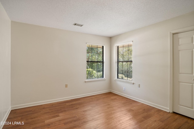 empty room with hardwood / wood-style flooring and a textured ceiling