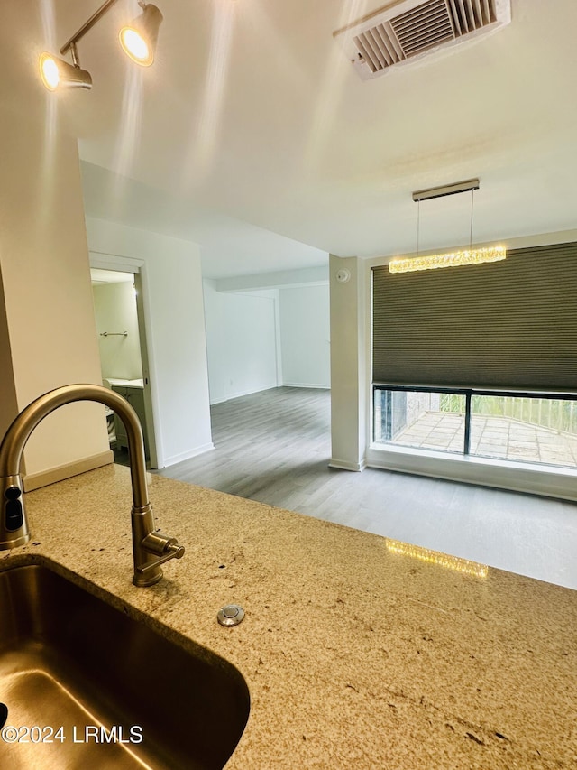 kitchen with pendant lighting, light stone countertops, sink, and hardwood / wood-style floors