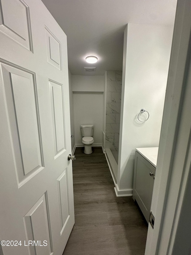 bathroom featuring vanity, hardwood / wood-style floors, walk in shower, and toilet