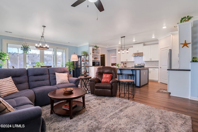 living room with crown molding, ceiling fan with notable chandelier, and light hardwood / wood-style flooring