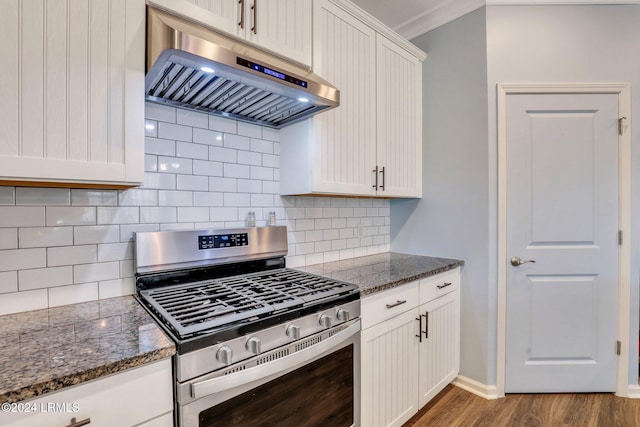 kitchen featuring exhaust hood, white cabinetry, stainless steel gas stove, dark stone countertops, and backsplash