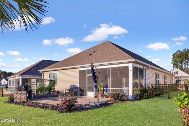 rear view of house with a sunroom, a lawn, and a patio area