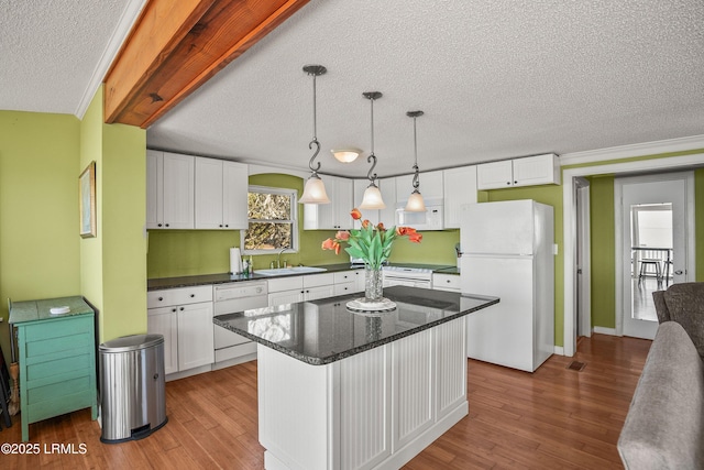 kitchen featuring sink, white appliances, white cabinetry, hanging light fixtures, and a kitchen island