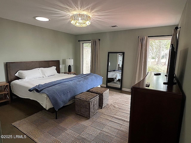 bedroom featuring multiple windows, wood finished floors, visible vents, and baseboards