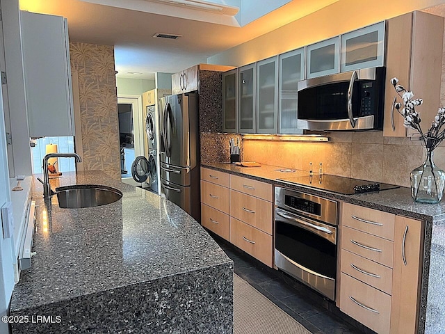 kitchen with tasteful backsplash, glass insert cabinets, stainless steel appliances, and a sink