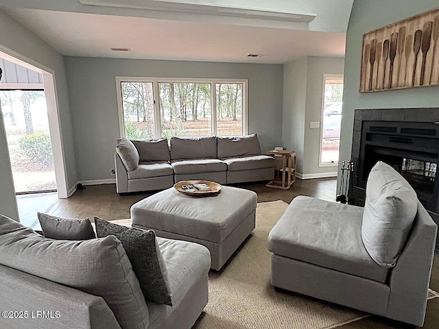 living room featuring a wealth of natural light, visible vents, a fireplace, and wood finished floors