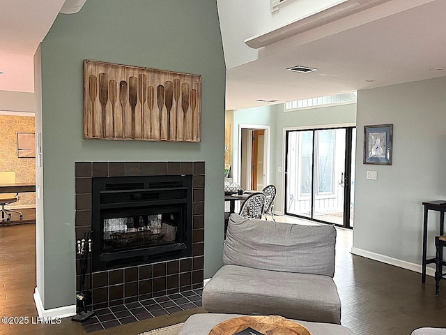 living room with baseboards, a fireplace, visible vents, and dark wood finished floors