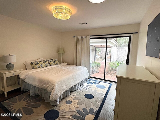 bedroom with wood finished floors, visible vents, and access to exterior