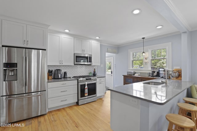 1413 Pigeon Point Rd, Beaufort, SC 29902 - kitchen featuring appliances with stainless steel finishes, crown molding, white cabinetry, a kitchen breakfast bar, and a sink