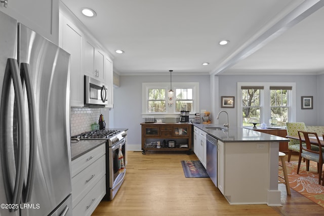 1413 Pigeon Point Rd, Beaufort, SC 29902 - kitchen featuring appliances with stainless steel finishes, a sink, a peninsula, light wood finished floors, and backsplash