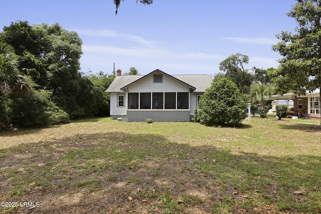 1413 Pigeon Point Rd, Beaufort, SC 29902 - rear view of house featuring a sunroom, a yard, a chimney, and roof with shingles