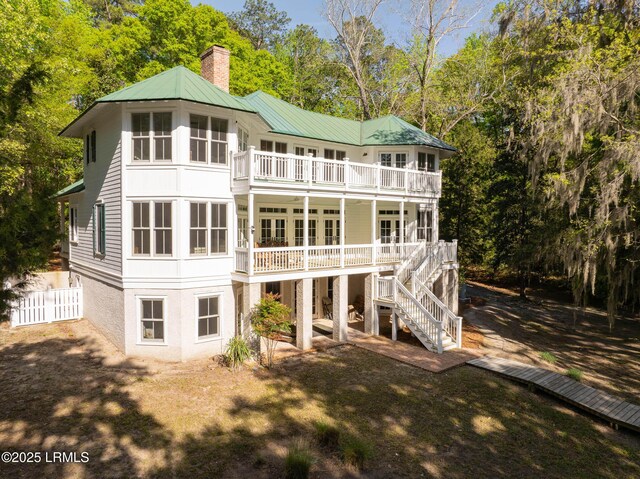 104 Barnaby Blf, Seabrook, SC 29940 - rear view of house with a chimney, a balcony, view of wooded area, a metal roof, and stairs