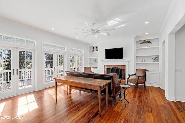 104 Barnaby Blf, Seabrook, SC 29940 - living room with a tile fireplace, ceiling fan, crown molding, wood finished floors, and built in shelves