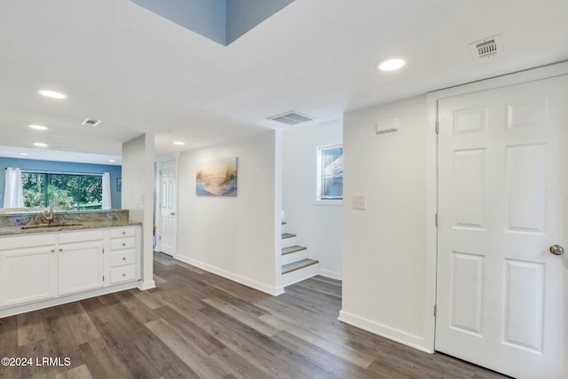 kitchen with white cabinetry, sink, hardwood / wood-style floors, and dark stone counters