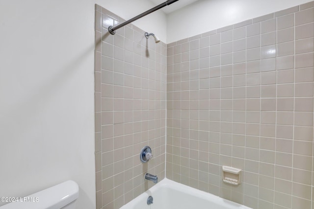 bathroom with tiled shower / bath combo and toilet