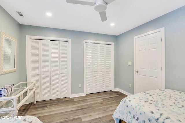 bedroom featuring two closets, light hardwood / wood-style flooring, and ceiling fan