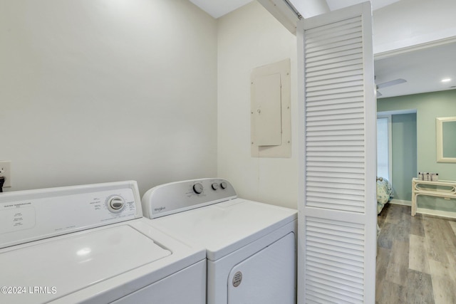 laundry area featuring independent washer and dryer, electric panel, and light hardwood / wood-style flooring