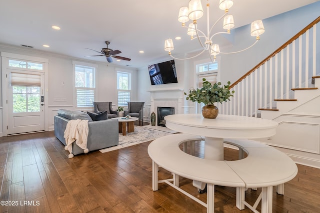 living area with dark wood finished floors, stairway, crown molding, a healthy amount of sunlight, and a decorative wall