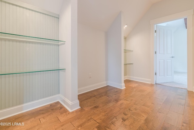 interior space featuring vaulted ceiling, light wood finished floors, and baseboards