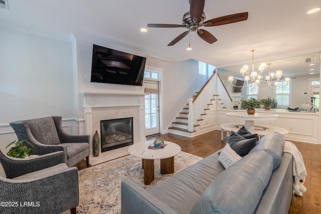 living area featuring visible vents, stairs, crown molding, a fireplace, and a decorative wall