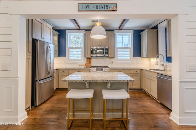 kitchen featuring a center island, light stone countertops, stainless steel appliances, pendant lighting, and a sink