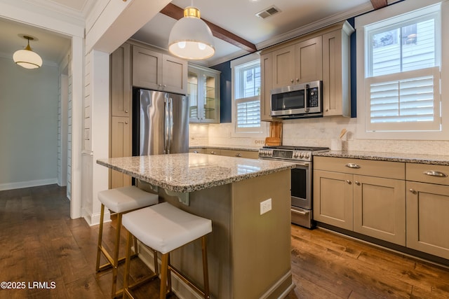 kitchen with light stone counters, pendant lighting, visible vents, appliances with stainless steel finishes, and glass insert cabinets