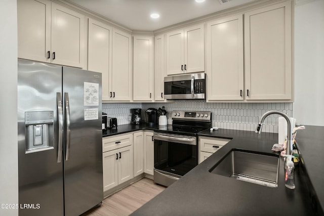 kitchen with stainless steel appliances, sink, light hardwood / wood-style floors, and decorative backsplash