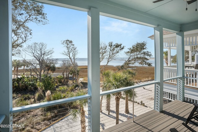 wooden deck with a water view and ceiling fan