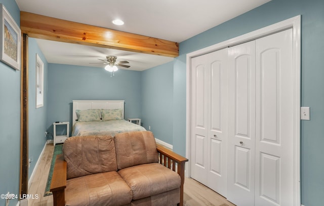 bedroom with ceiling fan, beam ceiling, light hardwood / wood-style floors, and a closet