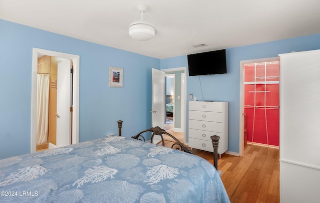 bedroom with a walk in closet, hardwood / wood-style floors, and a closet