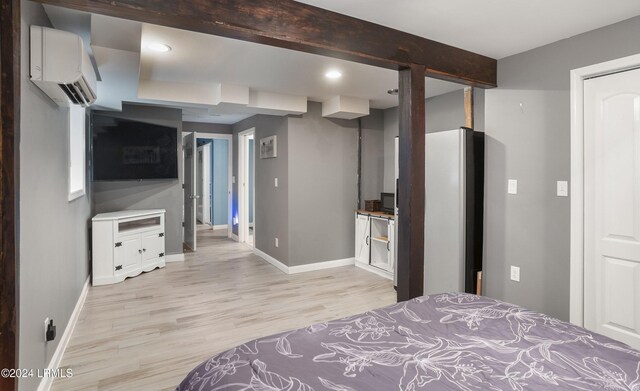 bedroom featuring stainless steel refrigerator, a wall mounted air conditioner, and light hardwood / wood-style floors