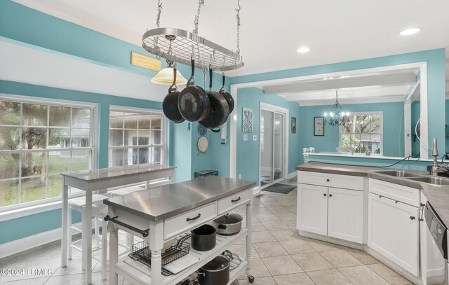 kitchen with beamed ceiling, dishwasher, a wealth of natural light, pendant lighting, and white cabinets