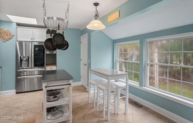 kitchen featuring a healthy amount of sunlight, stainless steel fridge with ice dispenser, hanging light fixtures, and white cabinets