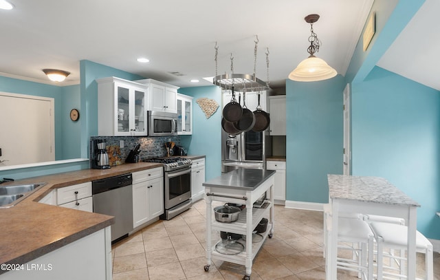 kitchen featuring sink, white cabinetry, hanging light fixtures, appliances with stainless steel finishes, and decorative backsplash